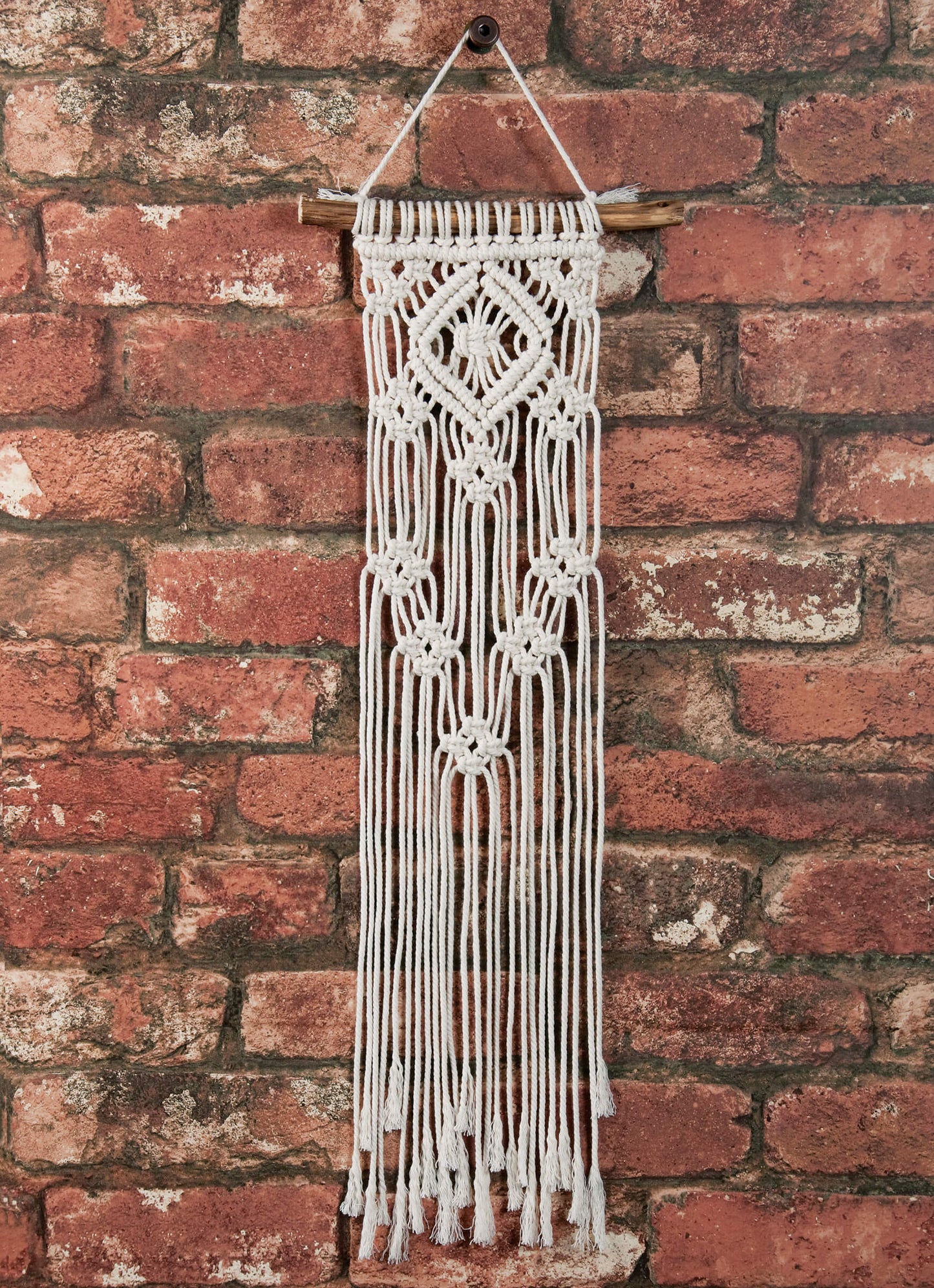 Solid Oak DIY macrame kit "Lacy Diamonds" design mini wall hanger, shown on brick background.