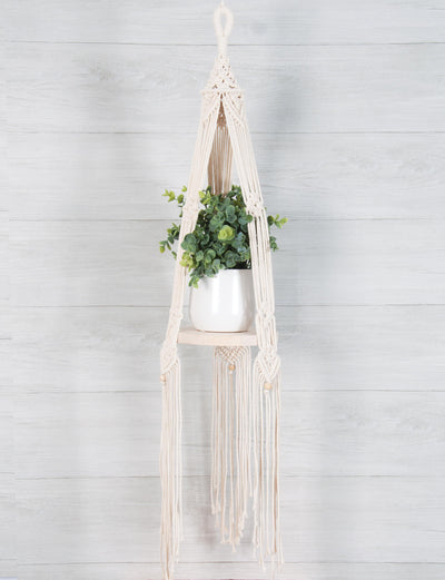 DIY macrame kit: round wood hanging shelf "Bohemian" style knotted design.shown with a plant against a light gray wood wall