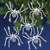 Picture of five silvery beaded Christmas spiders from SOlid Oak ornament kit, shown on greenery